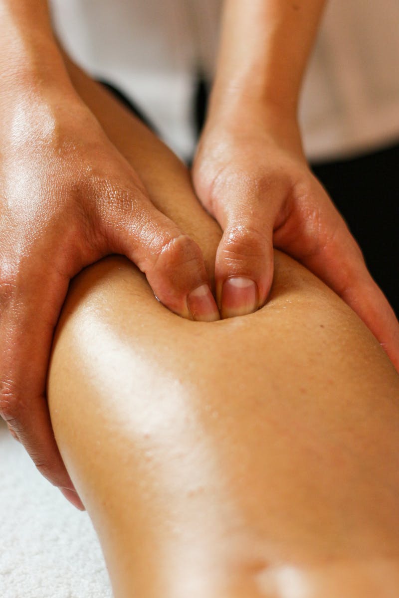Close-up of hands applying pressure on a leg during a therapeutic massage session.