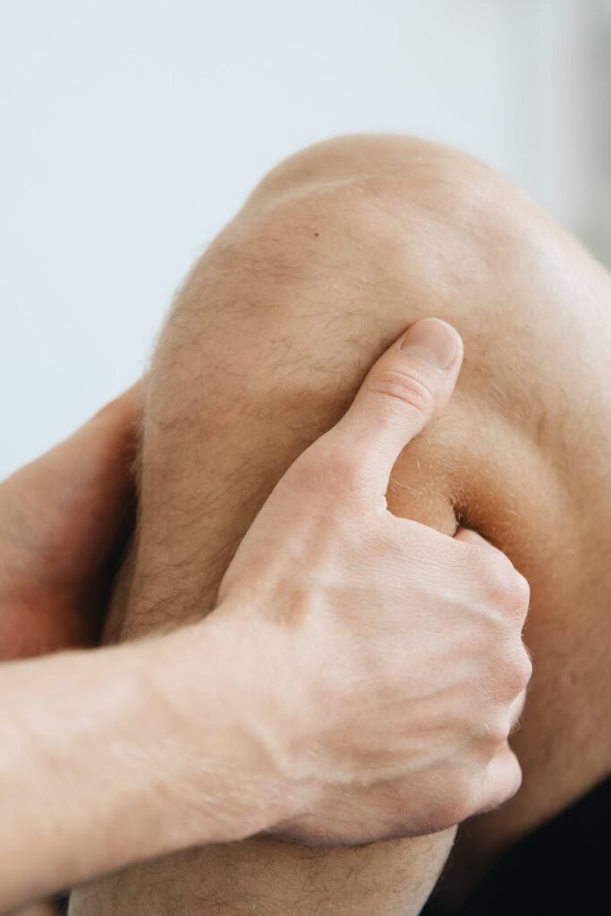 Close-up of a physiotherapist massaging a patient's knee during therapy.