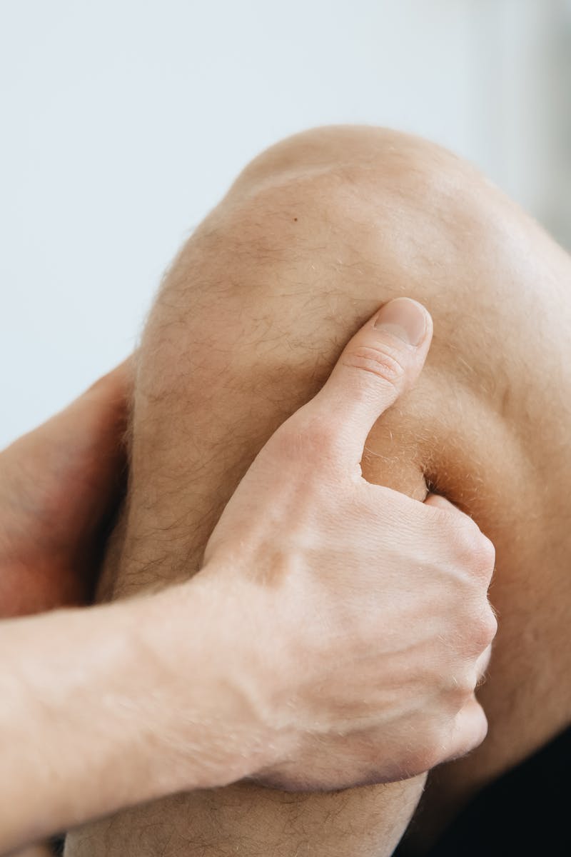 Close-up of a physiotherapist massaging a patient's knee during therapy.